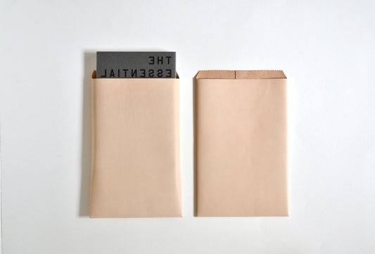 NUME FUTO Plusは、一般的な小説の単行本や青年コミック（B6判：182mm × 128mm）がぴったり収まる絶妙なサイズ感。 B6サイズのノートや小物もすっきりと持ち運べる、 素上げの牛ヌメ革素材の封筒型デザインが特徴のアイテムです。